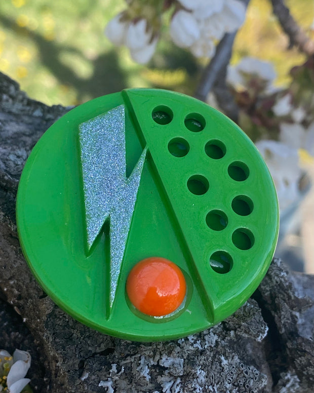 Broche verde con piedra naranja.